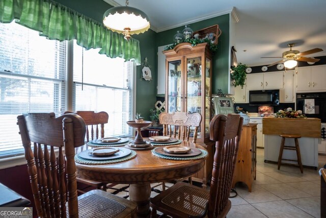 dining room with ceiling fan, ornamental molding, and light tile patterned floors