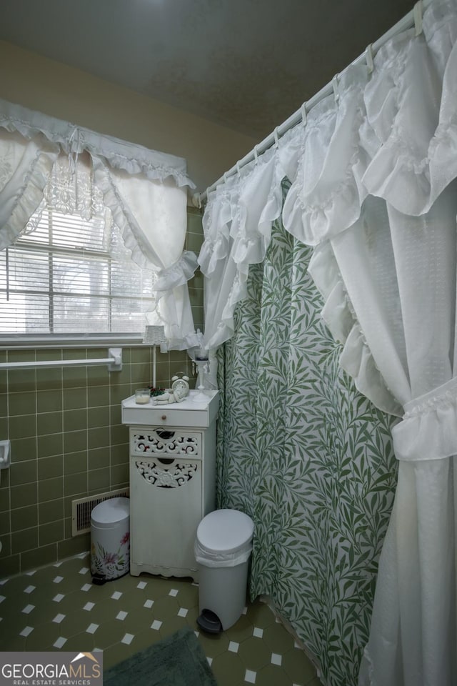 bathroom with tile patterned floors, visible vents, and tile walls