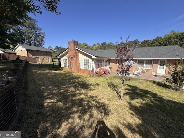 rear view of property with a patio area, a chimney, a lawn, a fenced backyard, and brick siding