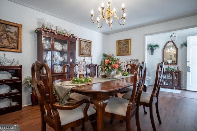 dining space featuring wood finished floors, ornamental molding, and a notable chandelier