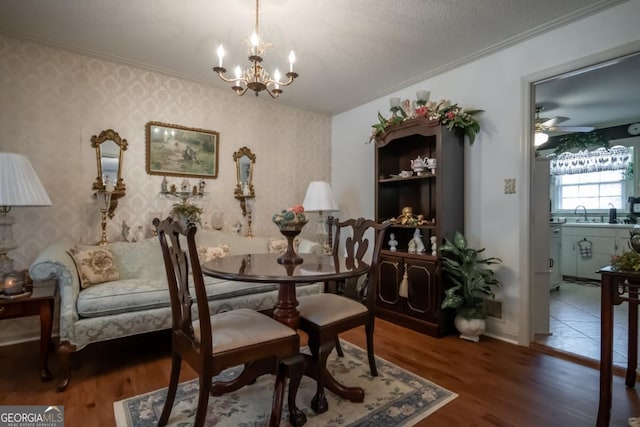 living area with dark hardwood / wood-style flooring, crown molding, ceiling fan with notable chandelier, and a textured ceiling