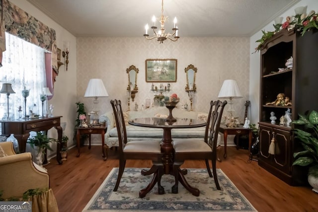 dining room featuring ornamental molding, a chandelier, wood finished floors, and wallpapered walls