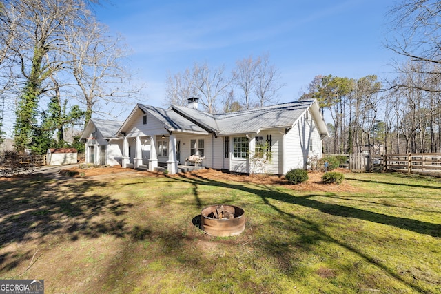 view of front of home featuring covered porch, a front yard, and an outdoor fire pit