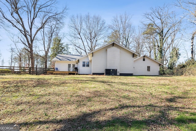 rear view of property with a deck, central AC unit, and a lawn