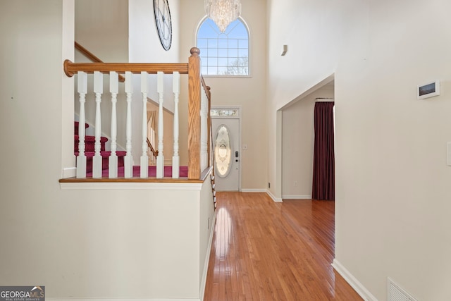 entrance foyer featuring a towering ceiling, a chandelier, and light wood-type flooring