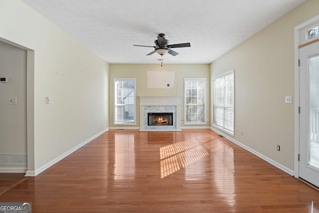 unfurnished living room with hardwood / wood-style floors, a wealth of natural light, a fireplace, and a textured ceiling