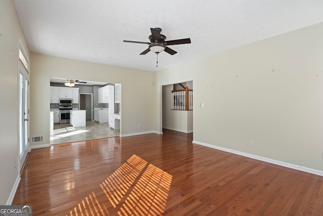 unfurnished living room with wood-type flooring and ceiling fan