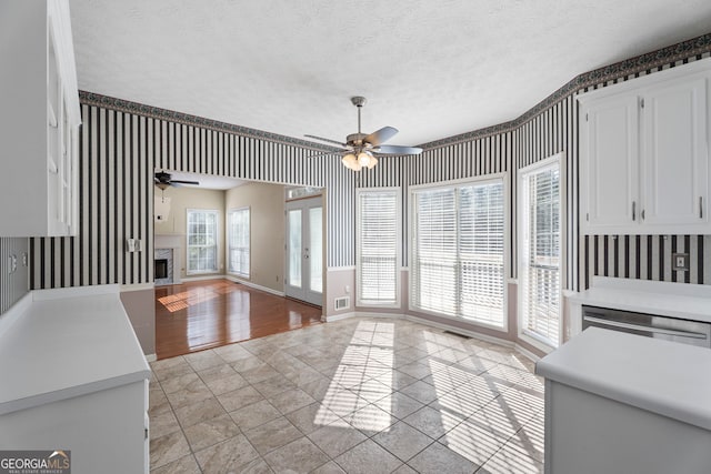 123 Stratmore Pl, Stockbridge, GA 30281 - unfurnished living room with ceiling fan, wallpapered walls, a textured ceiling, a fireplace, and light tile patterned floors