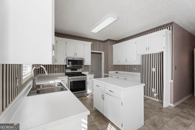 kitchen featuring white cabinetry, sink, stainless steel appliances, and a kitchen island