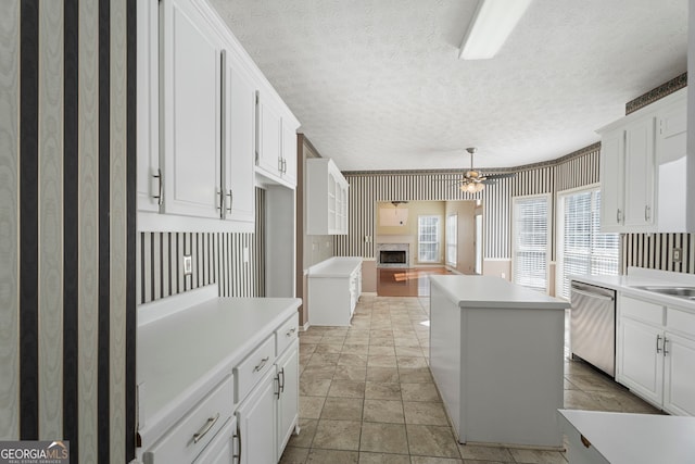 123 Stratmore Pl, Stockbridge, GA 30281 - kitchen with stainless steel dishwasher, wallpapered walls, a fireplace, ceiling fan, and white cabinets