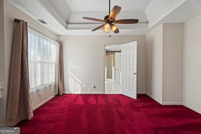 spare room with a textured ceiling, ornamental molding, a raised ceiling, carpet floors, and ceiling fan