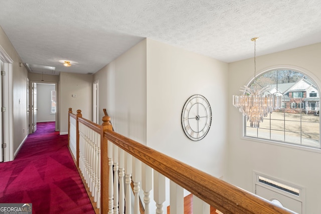 123 Stratmore Pl, Stockbridge, GA 30281 - hall featuring attic access, an upstairs landing, a textured ceiling, a chandelier, and carpet floors
