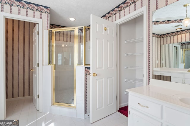 bathroom with tile patterned floors, vanity, an enclosed shower, and a textured ceiling