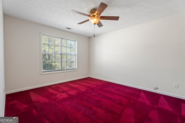 empty room with ceiling fan, a textured ceiling, and carpet flooring