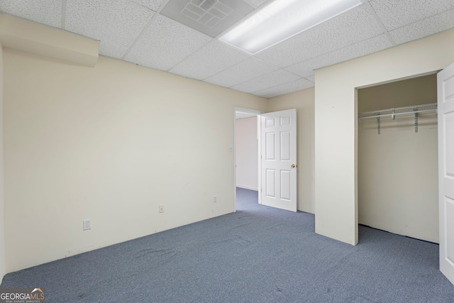 unfurnished bedroom featuring a paneled ceiling, a closet, and carpet