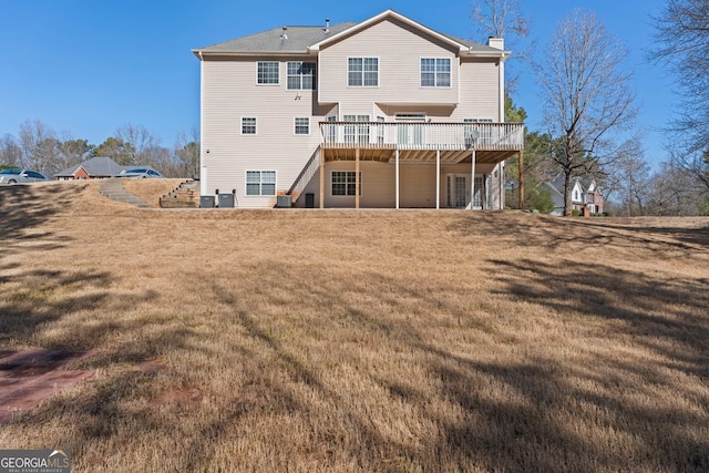 rear view of property featuring a wooden deck and a lawn