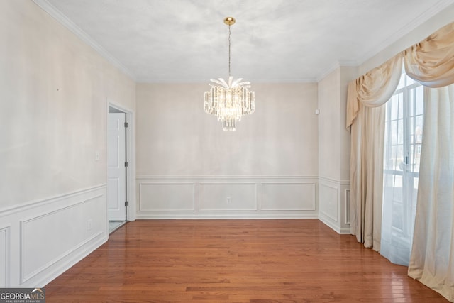 unfurnished dining area featuring ornamental molding, hardwood / wood-style floors, and an inviting chandelier