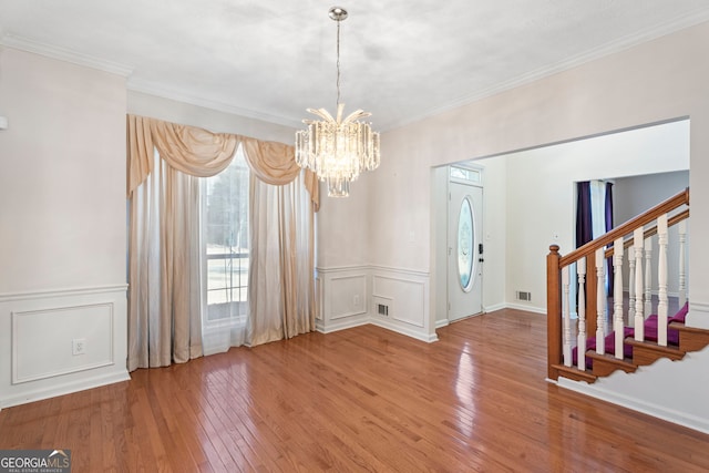 unfurnished dining area featuring crown molding, hardwood / wood-style floors, and a notable chandelier