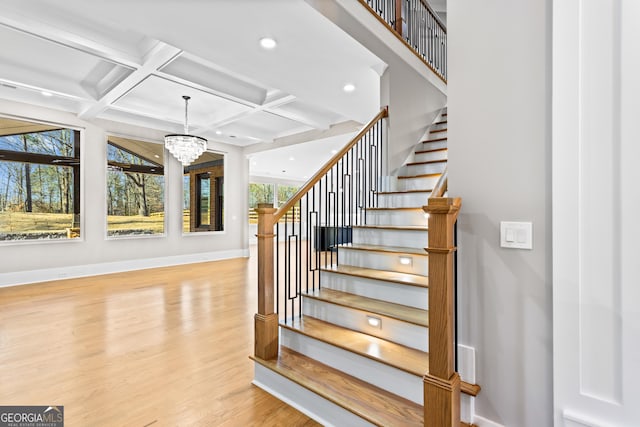 stairs with a chandelier, recessed lighting, coffered ceiling, wood finished floors, and baseboards