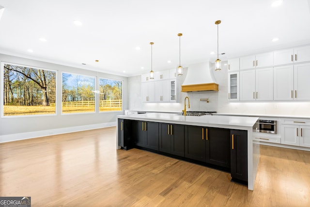 kitchen with light countertops, premium range hood, and white cabinetry