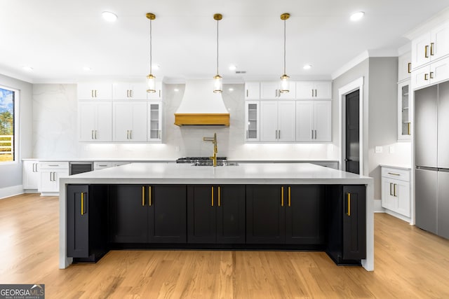 kitchen with ornamental molding, light countertops, stainless steel built in refrigerator, and premium range hood