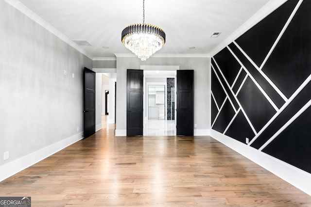 unfurnished room with a chandelier, ornamental molding, light wood-type flooring, and visible vents