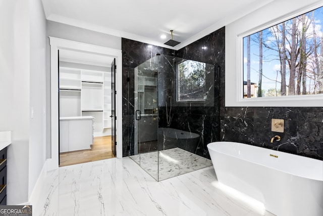 full bathroom featuring marble finish floor, a marble finish shower, a freestanding bath, a spacious closet, and vanity