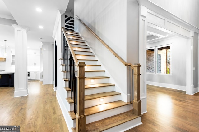 stairs featuring recessed lighting, decorative columns, baseboards, and wood finished floors