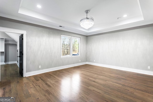 spare room with a tray ceiling and dark wood-type flooring