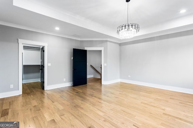 empty room featuring light wood-style floors, a tray ceiling, baseboards, and recessed lighting