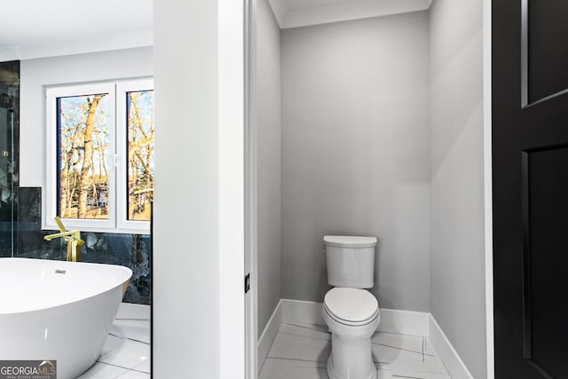 full bathroom featuring a freestanding bath, toilet, and baseboards