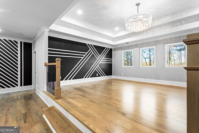 interior space with a tray ceiling, a healthy amount of sunlight, and wood finished floors