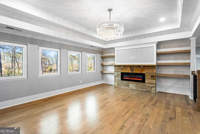 unfurnished living room with baseboards, visible vents, a raised ceiling, wood finished floors, and a fireplace