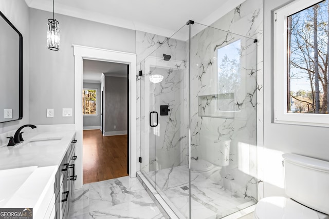 bathroom featuring marble finish floor, a marble finish shower, double vanity, toilet, and a sink