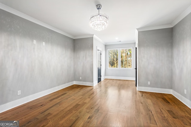 spare room with ornamental molding, wood finished floors, and baseboards