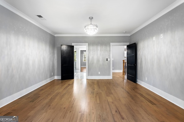 unfurnished bedroom featuring a chandelier, ornamental molding, wood finished floors, and visible vents