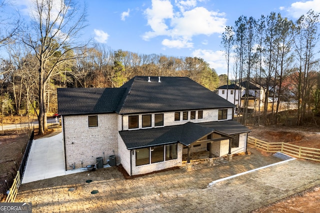 rear view of property featuring brick siding, fence, and central air condition unit