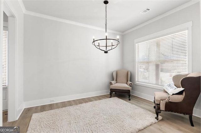 living area with light wood-type flooring, ornamental molding, and a chandelier