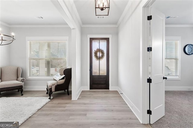 foyer with ornamental molding, a chandelier, and light hardwood / wood-style floors