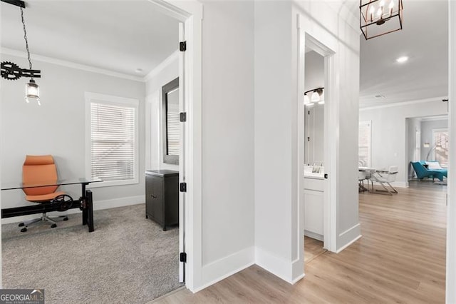 corridor featuring a notable chandelier, light hardwood / wood-style flooring, and crown molding