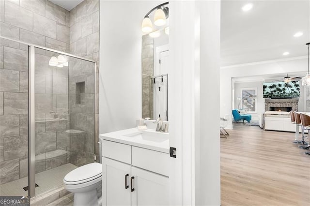 bathroom featuring toilet, vanity, a shower with shower door, and wood-type flooring