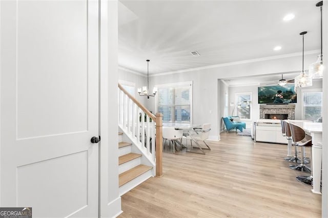 stairs with ornamental molding, hardwood / wood-style floors, and a notable chandelier