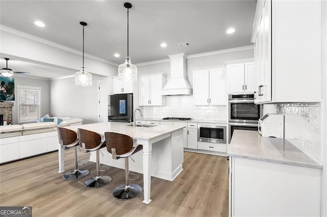 kitchen with white cabinets, appliances with stainless steel finishes, sink, and custom range hood