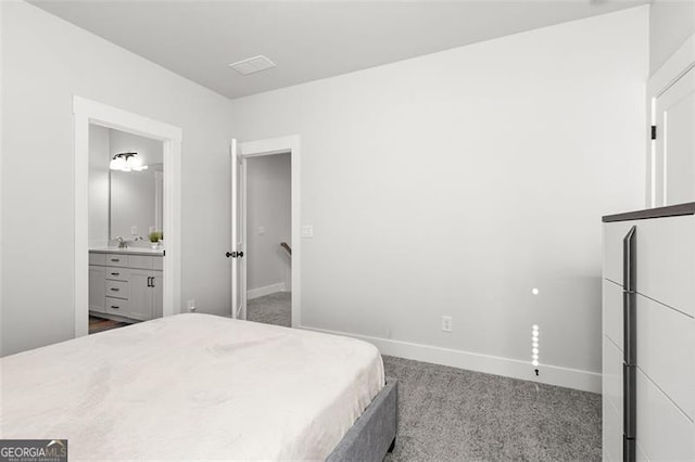 bedroom featuring connected bathroom, refrigerator, and carpet flooring