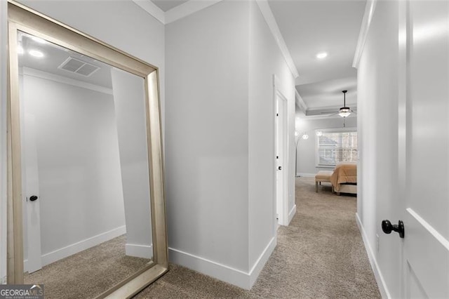 corridor with ornamental molding and light colored carpet