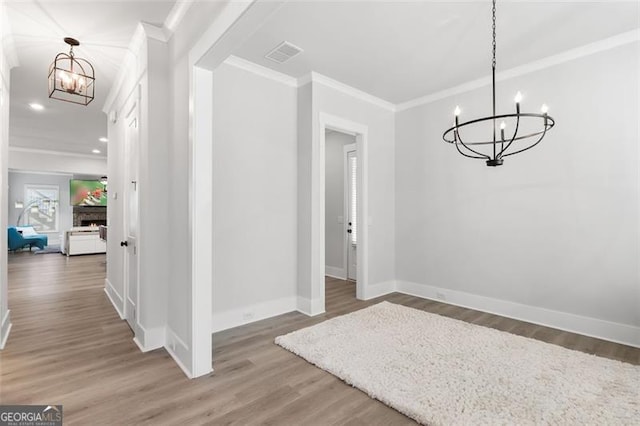 unfurnished dining area featuring a chandelier, crown molding, and hardwood / wood-style floors