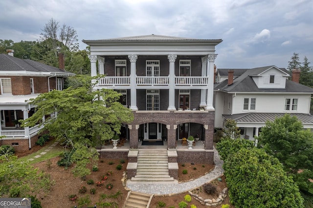 greek revival inspired property with a balcony and covered porch