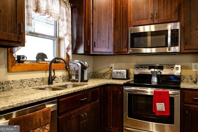 kitchen featuring stainless steel appliances, light stone countertops, and sink