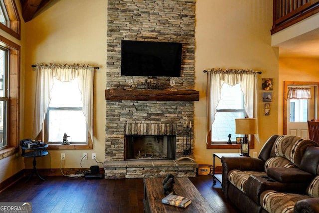 living room featuring a high ceiling, a wealth of natural light, hardwood / wood-style floors, and a fireplace