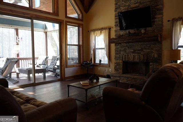 living room featuring a stone fireplace, wood-type flooring, and a high ceiling